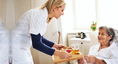 caregiver preparing meals to senior woman